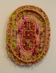 "Complications" by Louise Roby. Materials: Basket lid, beads & string. 21" x 16"
